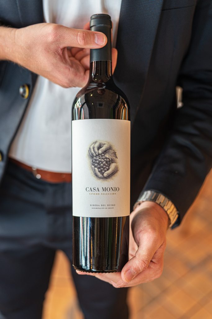 Camarero de Fino Bar presentando una botella de vino de la bodega seleccionada